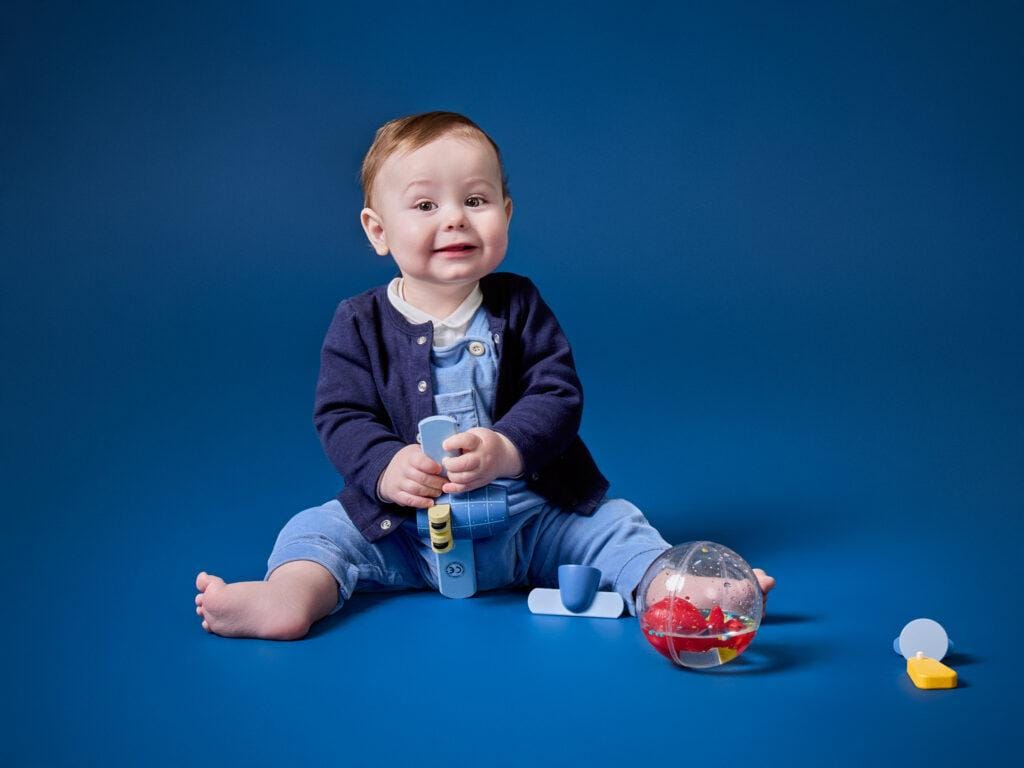 Photographie en studio d'un bébé assis avec ses jouets - Mon Aparté Bièvres
