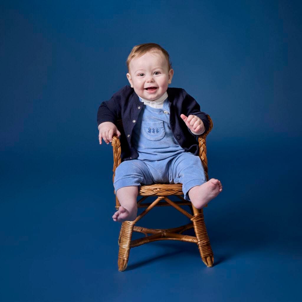 Photographie bébé assis sur une chaise en rotin studio à Bièvres